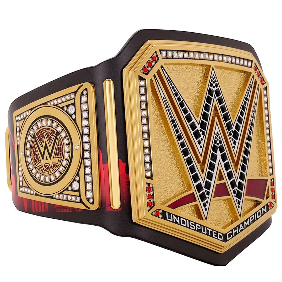 Side angle of a gold Undisputed Championship wrestling belt with crystal-encrusted logo and circular side plates.